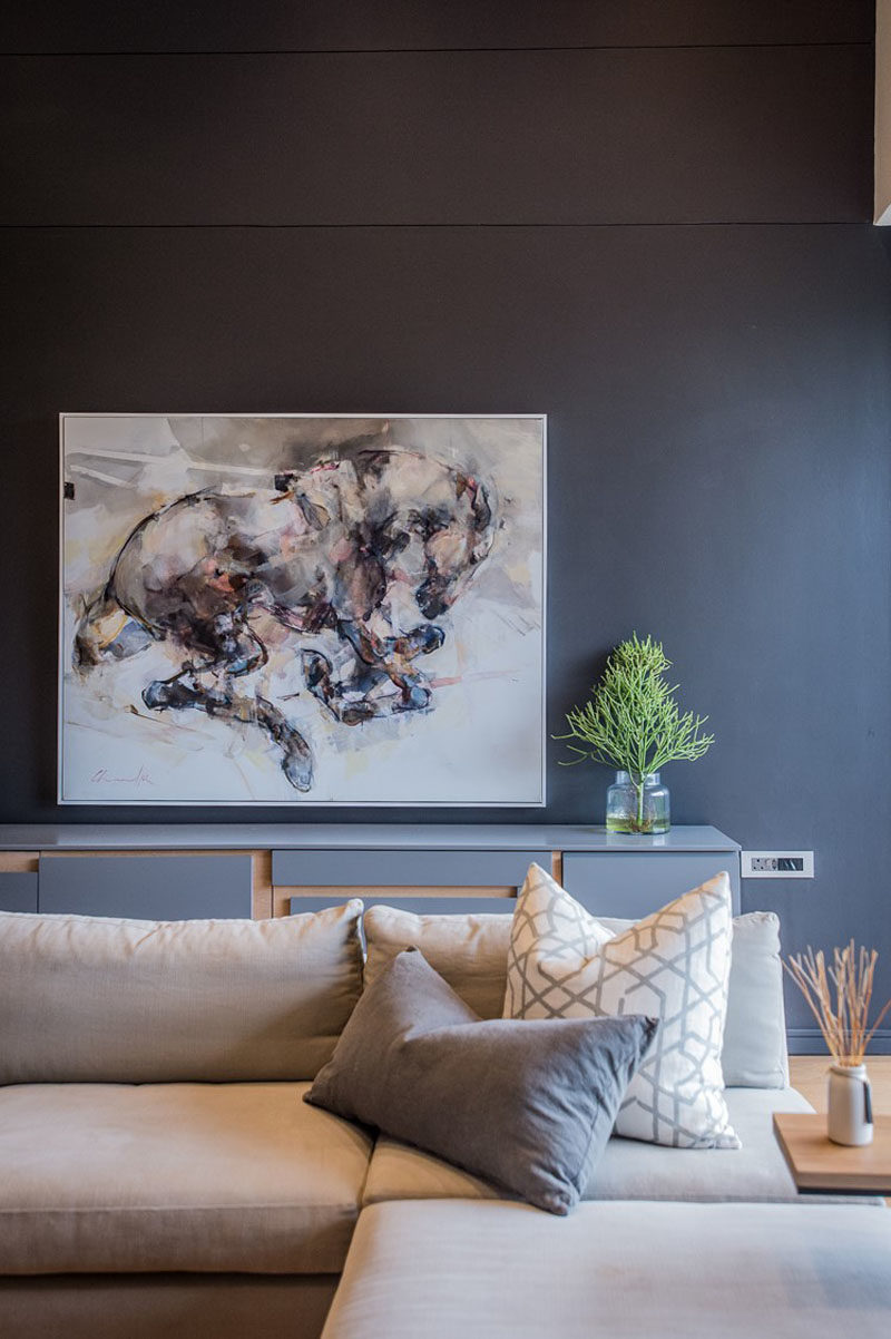 This modern living room features a dark accent wall that helps to make the artwork and light colored furniture stand out. #LivingRoom #DarkWall