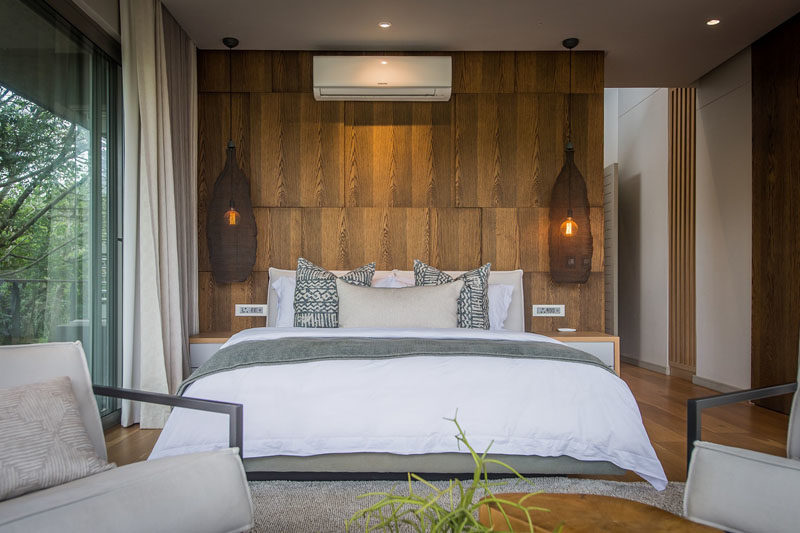 In this modern bedroom, a paneled wood accent wall showcases the grain, while delicate basket-like pendant lights hand on both sides of the bed. #BedroomDesign #BedroomIdeas #WoodAccentWall