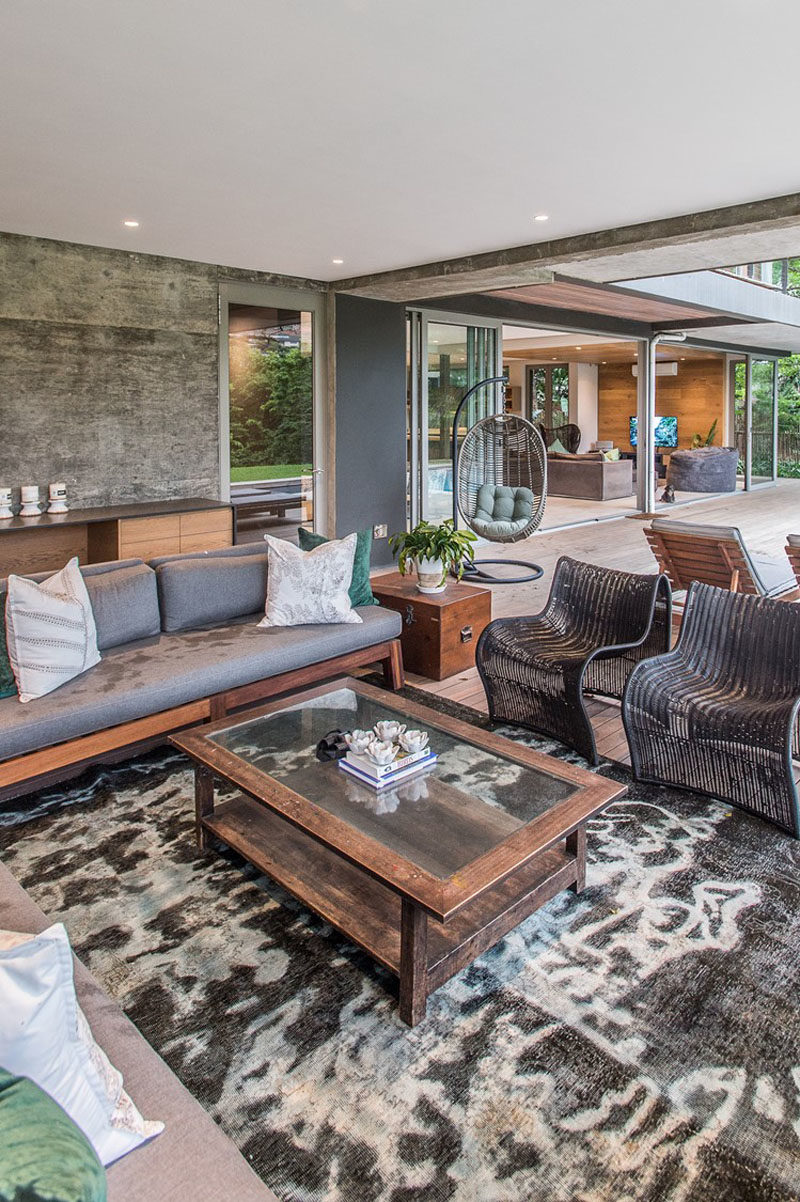 This modern house has a covered outdoor living room with multiple seating options. #OutdoorLivingRoom #InteriorDesign