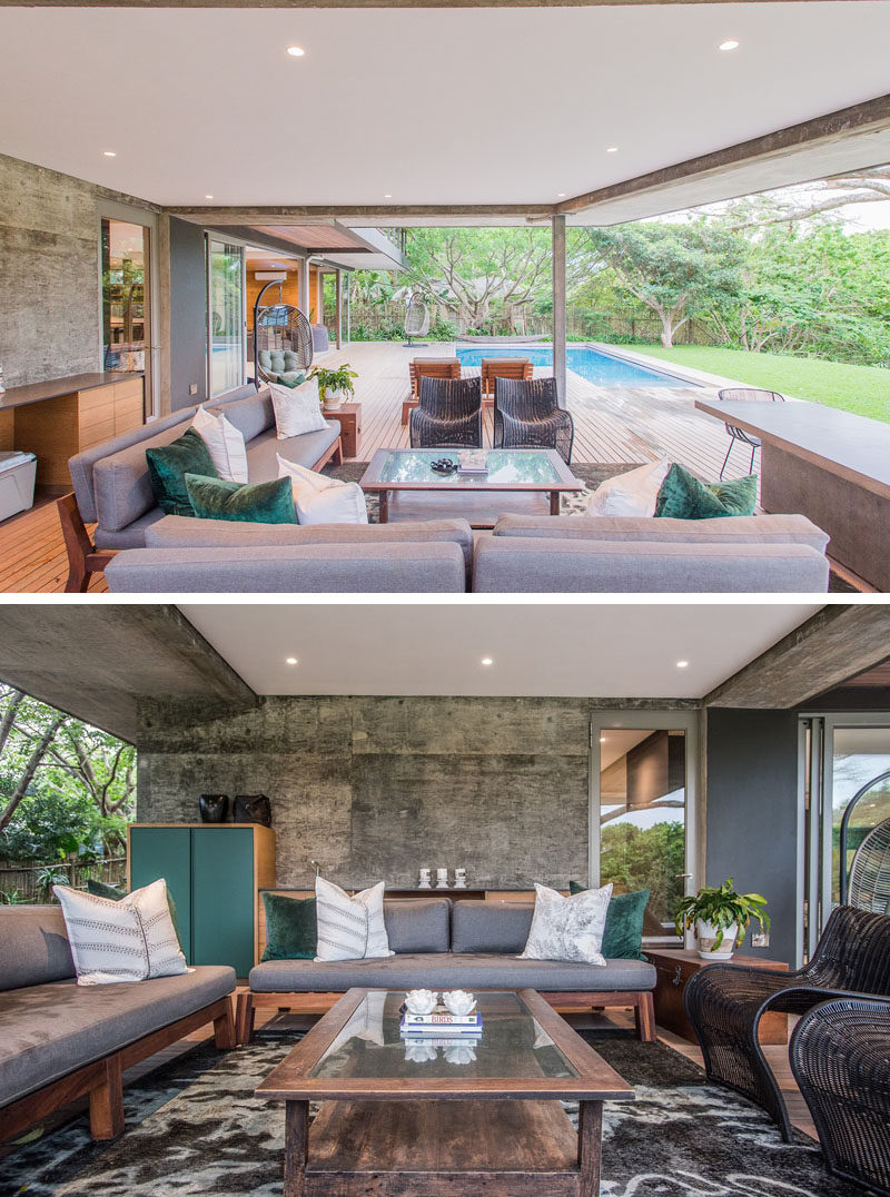 This modern house has a covered outdoor living room, fully furnished with couches, chairs, storage, and a table.  #OutdoorLivingRoom #OutdoorSpace