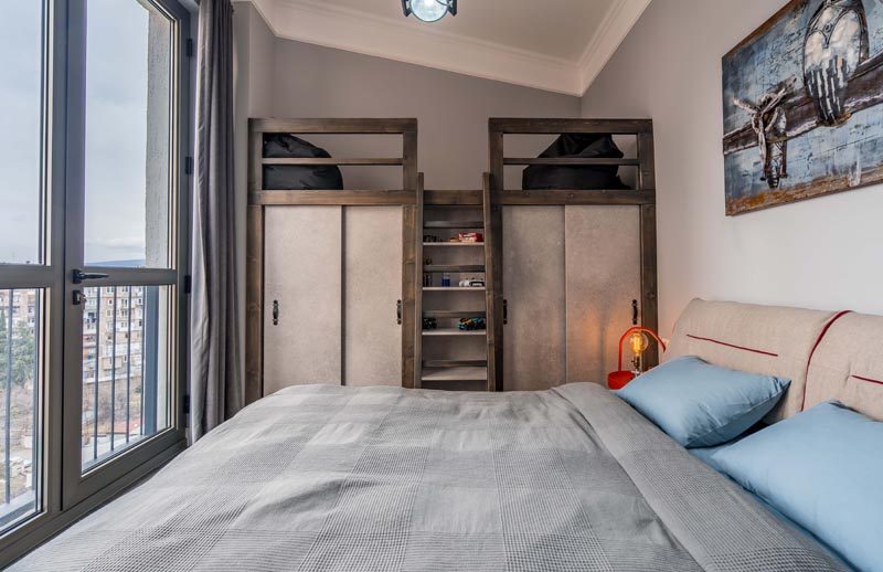 This modern bedroom has a lofted sitting area above the closets, that's accessed by a small ladder and furnished with beanbags. #LoftedLounge #BedroomDesign #BedroomIdeas #ModernBedroom #Loft #Closets
