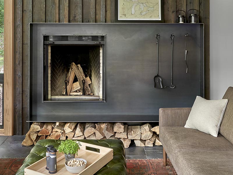 A modern living room in a weekend retreat features a hand-worked blackened steel fireplace surround. #Fireplace #BlackFireplaceSurround #SteelFireplace