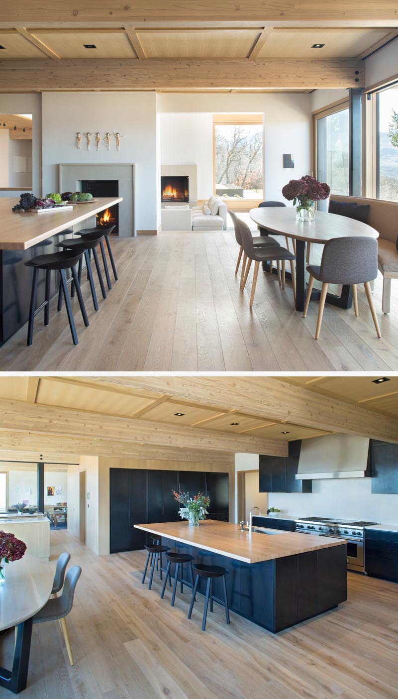 In this modern open plan breakfast nook and kitchen, there's a fireplace and minimalist black cabinets that have been combined wood details, like the large wood island countertop. #ModernKitchen #Fireplace #BlackKitchenCabinets