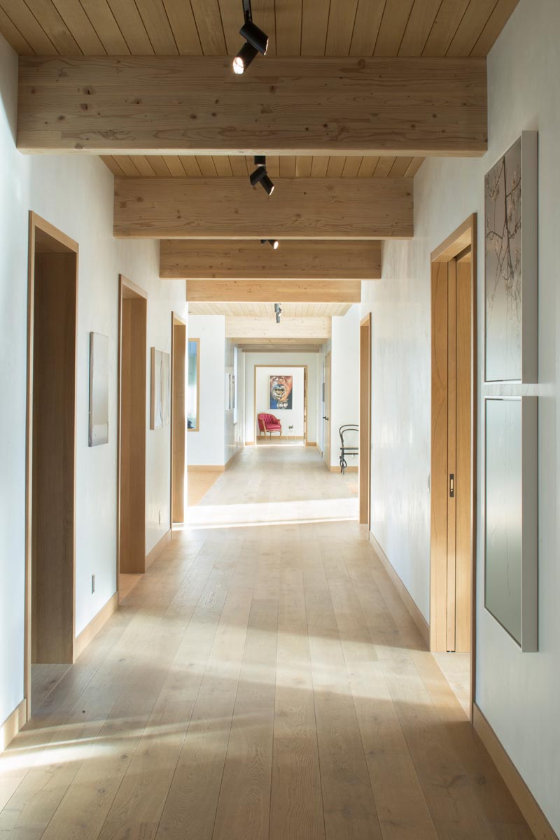 A hallway running the length of this house has wood framed doors that provide access to the various other areas of the house. #ModernHallway #WoodFloors