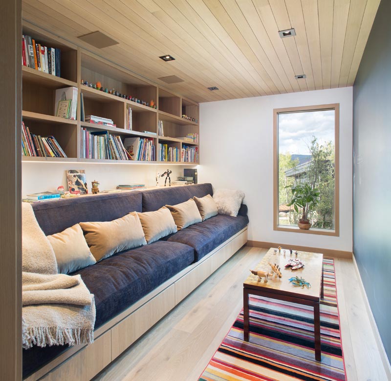 This modern room's dedicated to reading and playing, with a comfortable couch and shelving that runs the length of the room. #ModernReadingRoom #ModernPlayRoom #ModernHomeLibrary