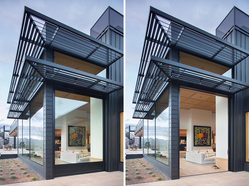 A large black-framed glass pocket door opens connects the living room with the exterior of this modern house. #Doors #PocketDoor