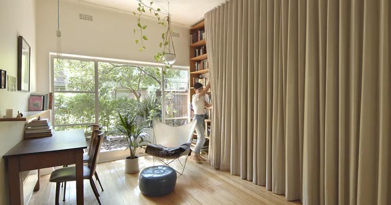 A Floor-To-Ceiling Curtain Hides A Wall Of Storage And Bed In This