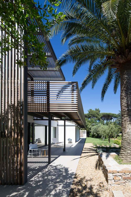 A walkway on a higher level provides shade for the lower outdoor spaces.