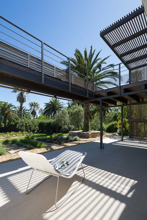 A walkway on a higher level provides shade for the lower outdoor spaces.