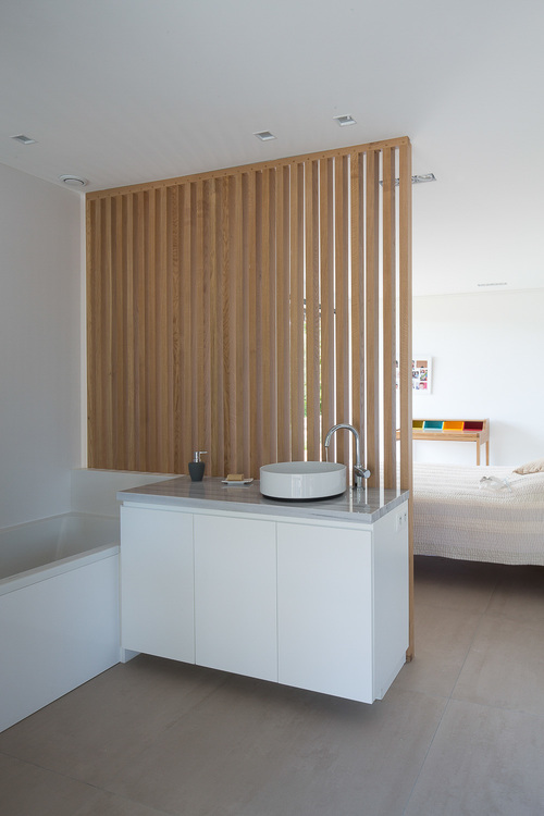 This ensuite bathroom is partitioned from the bed with a wooden slat wall.