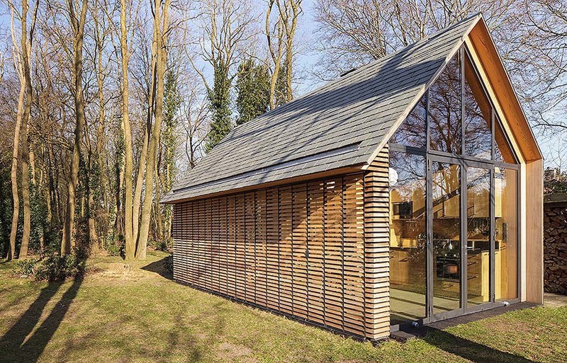 This modern cottage has a wall of windows one end, while windows with wood slat shutters line another wall.