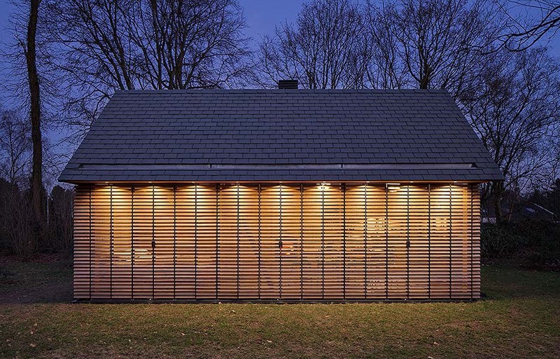 Windows with wood slat shutters line the side wall of this modern cottage, creating an open feeling, while at night, the shutters can be closed for more privacy.