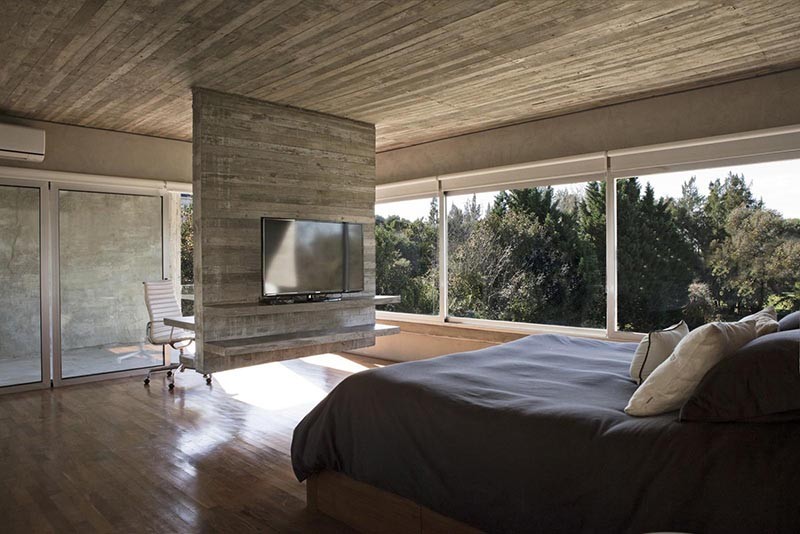 Hanging concrete room divider with a television on one side, and a desk on the other.