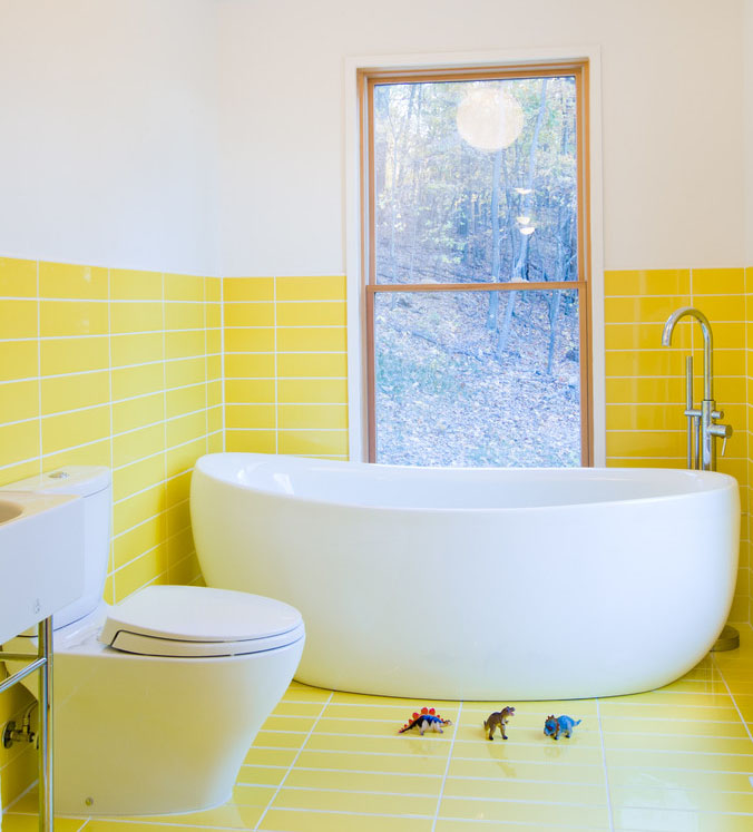 Yellow tiles on the floor and wall of this bathroom