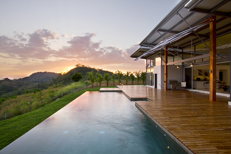 An infinity edge swimming pool with an expansive wood deck.