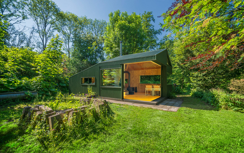 A small cabin with a green exterior and a wood-lined interior.