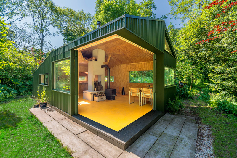 A small cabin with sliding doors that open up to a garden.