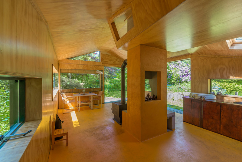 A small cabin with a fireplace and plenty of windows.