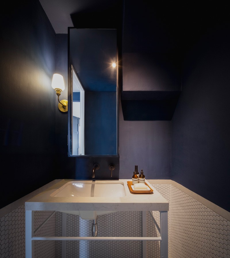 A deep blue and white powder room that features penny tiles. #ModernPowderRoom #BluePowderRoom #WhitePennyTiles