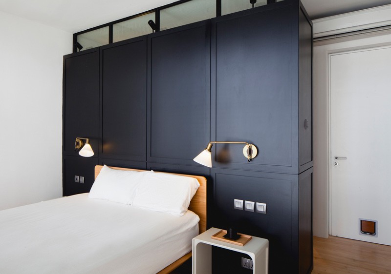 A modern bedroom with a black headboard and sconces. #ModernBedroom #BlackHeadboard #Sconces