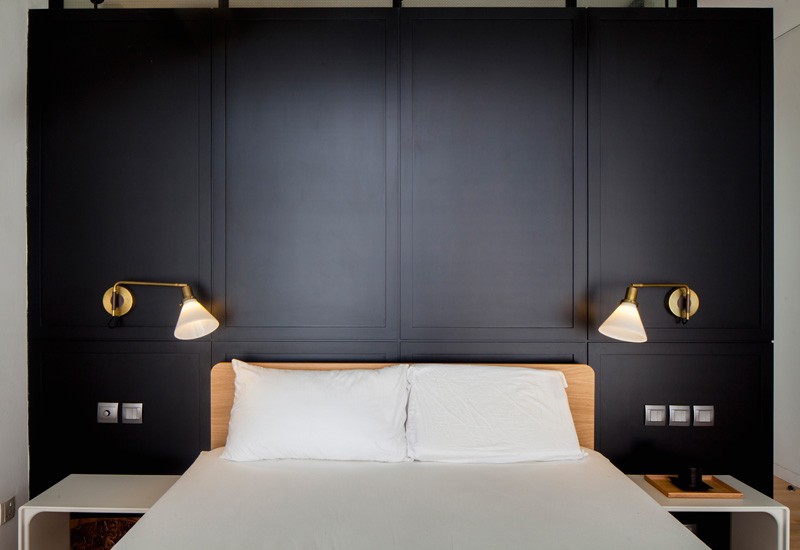 A modern bedroom with a black headboard and sconces. #ModernBedroom #BlackHeadboard #Sconces
