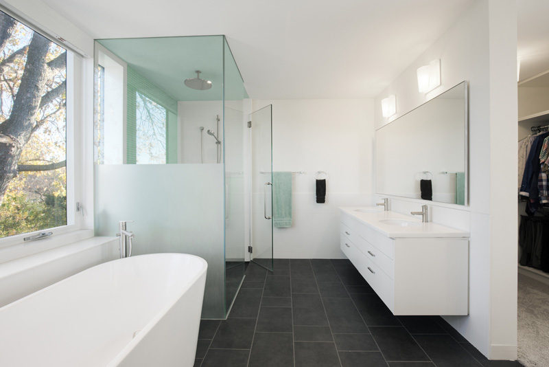 This bathroom has a walk-in shower with rainfall showerhead, a standalone bathtub, and a vanity with double sinks.