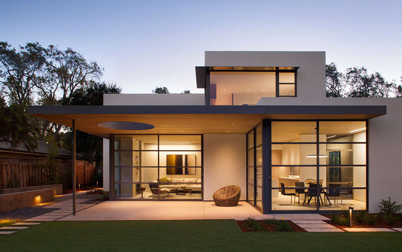 This modern house has a covered patio and floor-to-ceiling glass walls.