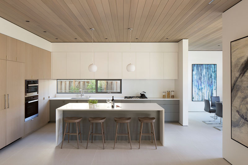 This modern kitchen is connected to the living room and dining room by a floating cedar ceiling. #KitchenDesign #WoodCeiling