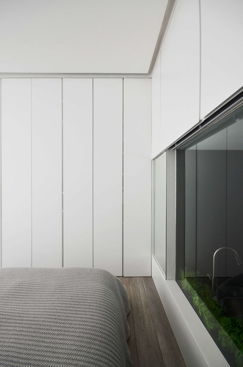 In this bedroom, walls of white cabinets travel from the floor to the ceiling. There's also a window into the kitchen, that can be covered for privacy.