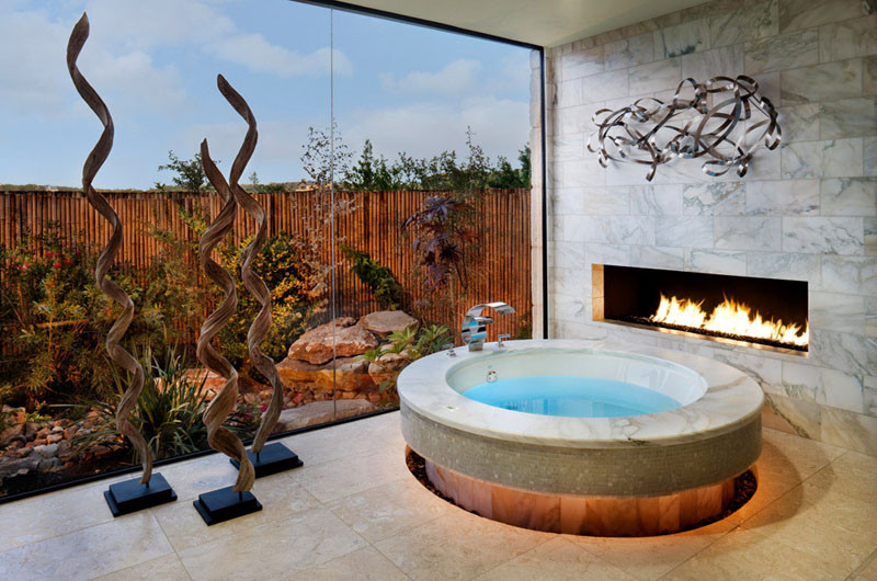 This circular bathtub has a fireplace right next to it for ultimate relaxation.