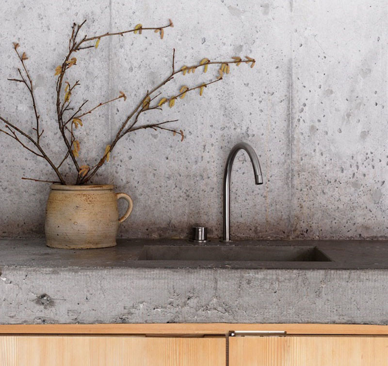 Concrete is popular in kitchens because of its durability and versatility. It can come in many colors and can be custom-shaped. Concrete is a somewhat porous material, so it definitely needs a surface sealant applied to make it water and stain resistant. #KitchenBacksplash #ConcreteBacksplash #KitchenDesign #BacksplashIDeas