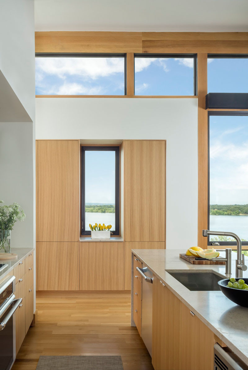 This light wood kitchen has stainless steel appliances and views of the water. // Blue Lake Retreat by Lake|Flato Architects