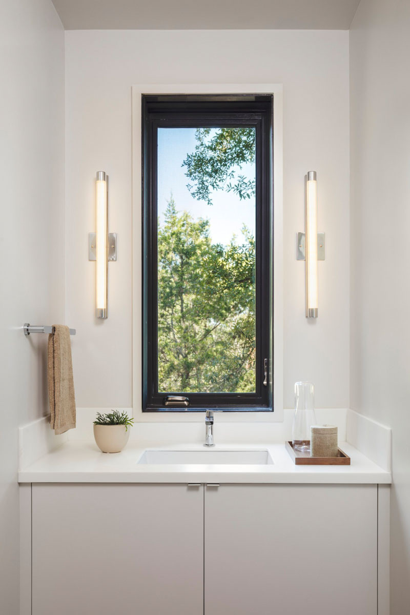 In this bathroom, there is a mirror that slides out to cover the window, otherwise it just has a picturesque view of the trees outside. // Blue Lake Retreat by Lake|Flato Architects