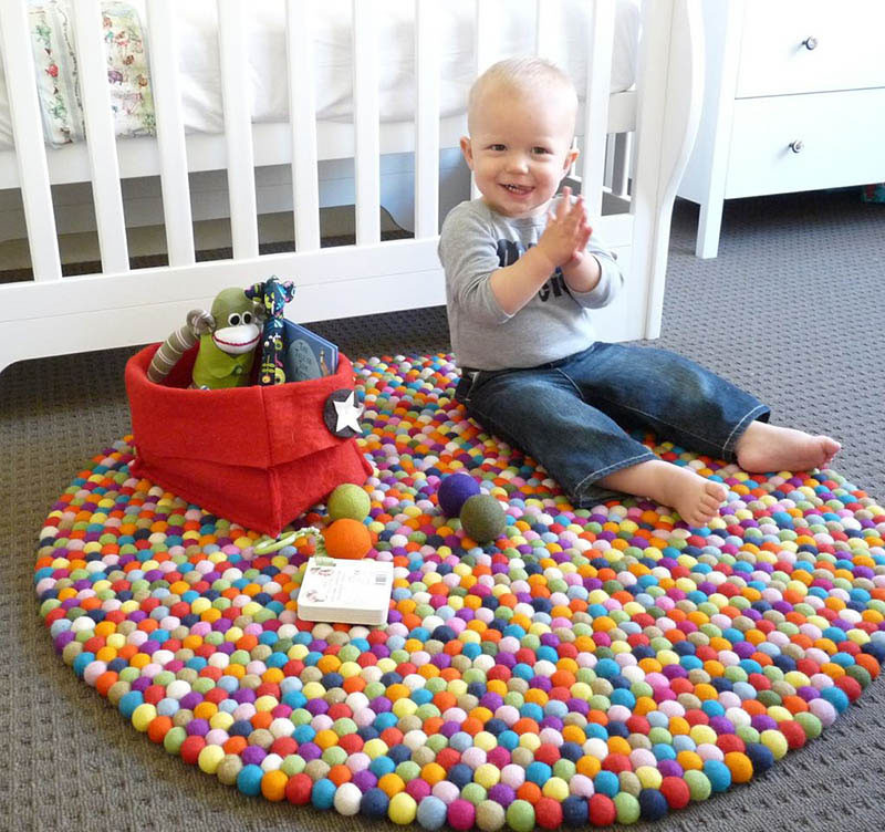 Lots of colored felt balls make up this round rug. #KidsRug #ColorfulRug #ModernRug #NurseryRug
