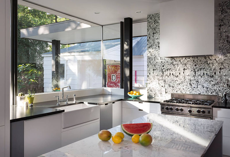 This white farmhouse sink blends in with the kitchen cabinets, that contrast the dark countertop.