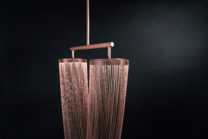 These sculptural lights are made from delicate copper plated chains that hang from two circular forms to create a unique curved shape, all of which is illuminated by a ring of LED lights. #Lighting #SculpturalLighting #LightingDesign #Chandelier #CopperLighting