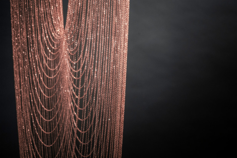 These sculptural lights are made from delicate copper plated chains that hang from two circular forms to create a unique curved shape, all of which is illuminated by a ring of LED lights. #Lighting #SculpturalLighting #LightingDesign #Chandelier #CopperLighting