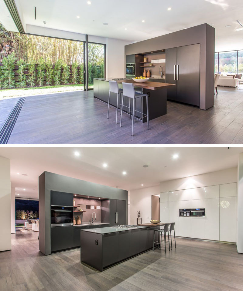 A partial wall separates the kitchen from the dining and living area. It also has an island with a cantilevered wooden counter, making room for bar stools.