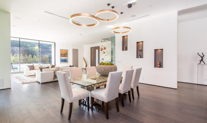 This dining area and living area share the same space, however sculptural lighting helps to define the location of the dining area. 