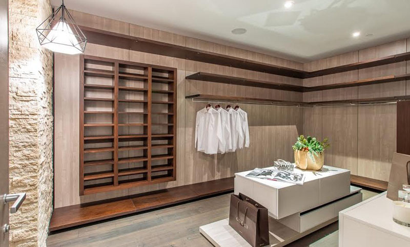 This walk-in closet has plenty of wooden cabinetry and shelves, as well as a central island for storing your accessories.