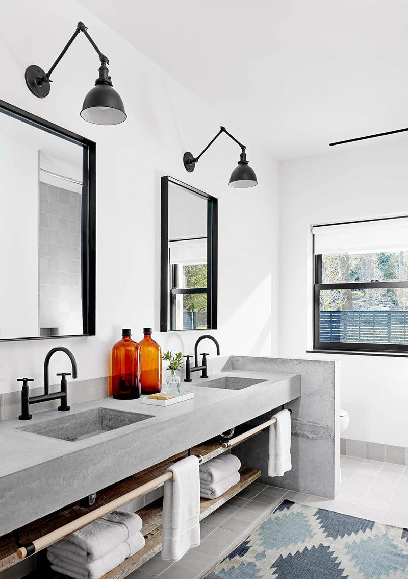 15 Examples of Bathroom Vanities That Have Open Shelving // The custom made concrete vanity in this master bathroom, has dual sinks, a towel railing and open shelving.