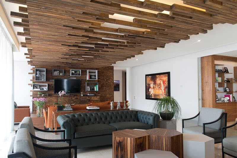 When Kababie Arquitectos were designing this apartment in Mexico City, they decided to define the living room by installing a decorative wooden feature that wraps from one end of the room, onto the ceiling, and then down the wall on the other end.