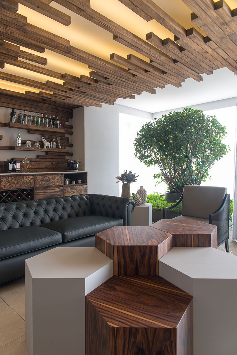 At the end of this living room is a lounge and bar. The floating shelves above the bar blend into the ceiling details, creating a unified and seamless look.