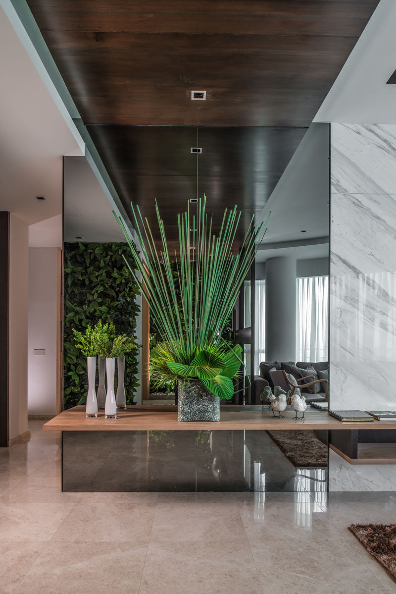 Upon entering this home, there is greenery everywhere, like the green walls and this arrangement positioned in front of a mirror.