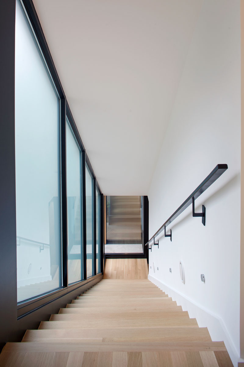 Light wood stairs contrast the black window frames and handrail in this home.