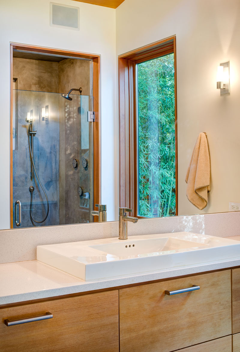 This master bathroom has a wood framed window that matches the frame on the shower door.