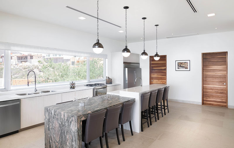 This kitchen has a large window running the length of the counter, and a dual-height island, providing plenty of space for meals and entertaining.