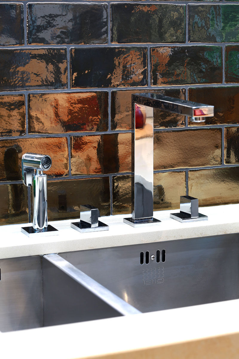 A stainless steel undermount sink and faucet, and dramatic dark bronze tiles have been used in the design of this kitchen.