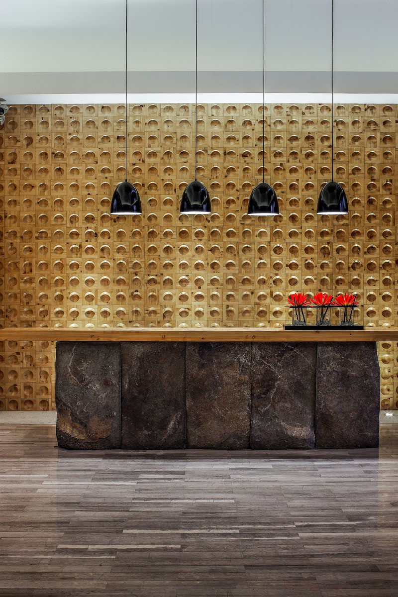 This spa reception area has a large desk, with the dark stone contrasting the wooden feature wall.