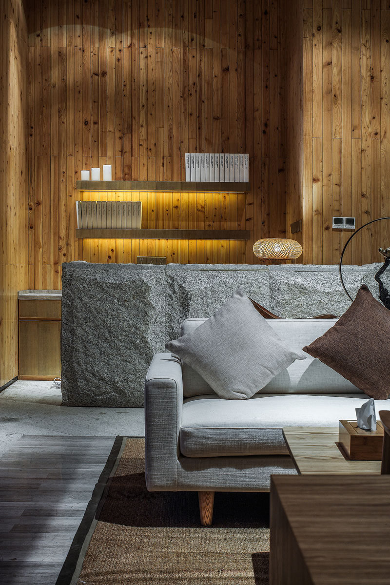 A lighter colored stone has been used as a feature material in this lounge area of a spa, and smaller design elements, like hidden lighting under the floating shelves have also been included.